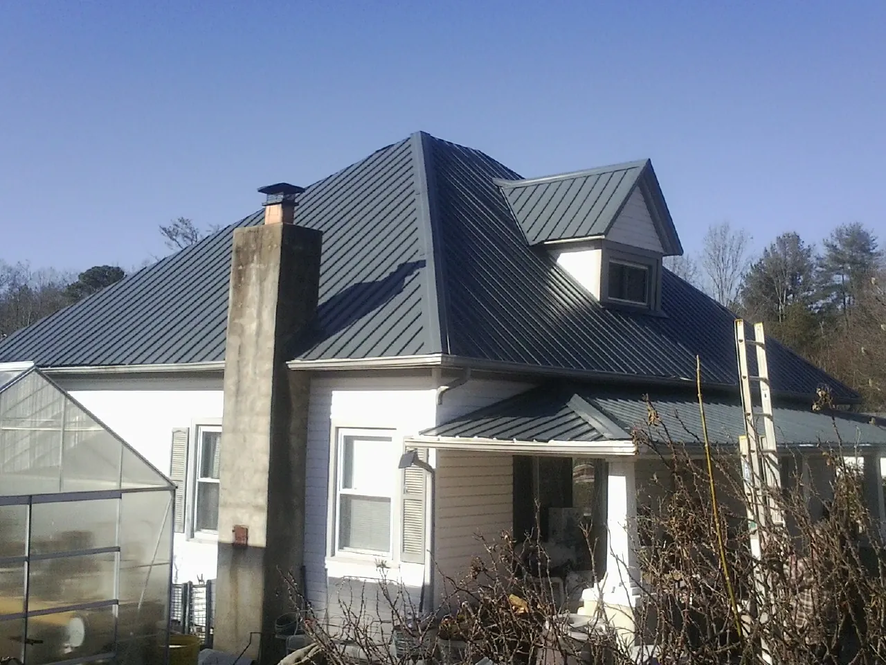 Dark blue standing seam metal roof on a white farmhouse with dormer — Slate & Tile Roof Repair by Roofing Brothers in Falling Waters