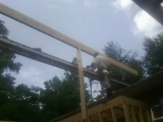 Carpenter setting a ridge beam over a new addition frame — Ice Dam Removal by Roofing Brothers in Falling Waters