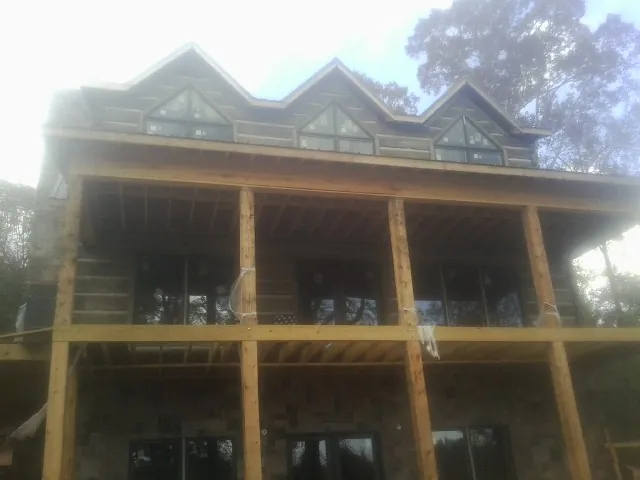 Dormers and porch framing on a large log home under construction — Roof Coating work by our crew in Falling Waters