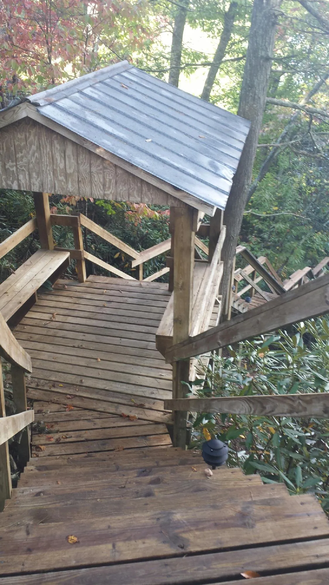 Metal roofed shelter over wooden steps on a wooded walkway — Skylight Repair & Installation work by our crew in Falling Waters