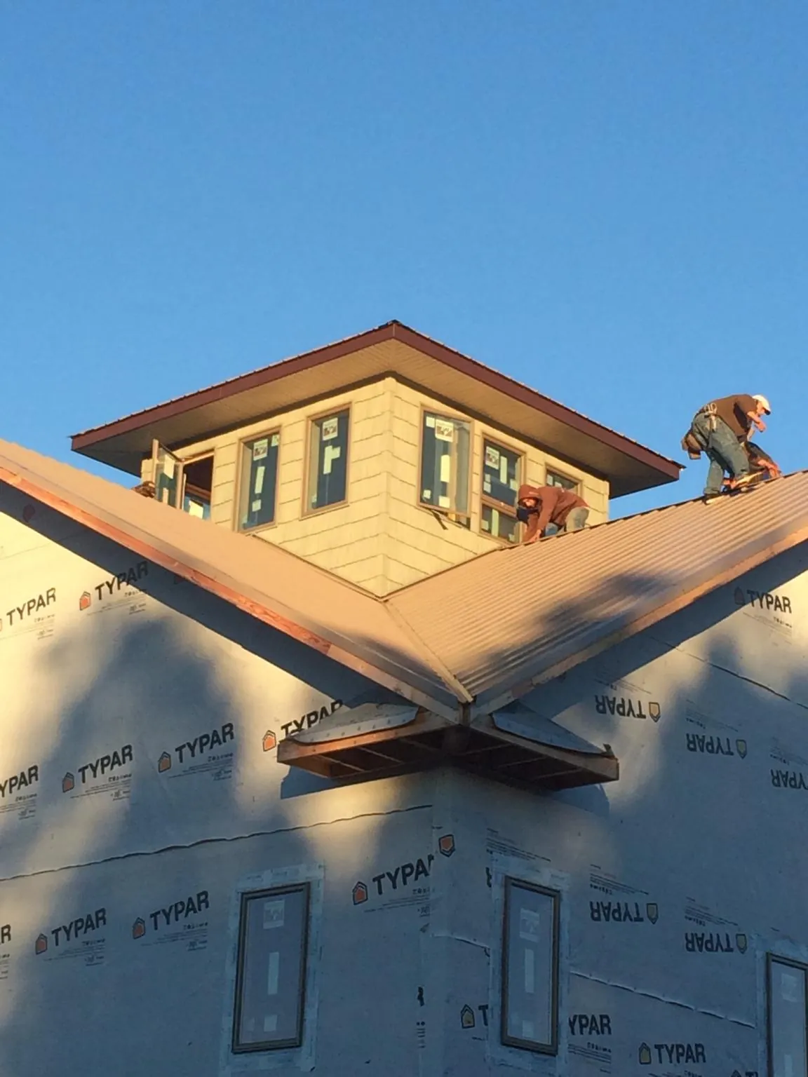 Roofers working around a rooftop cupola on a new metal roof at sunset — Roof Waterproofing in Falling Waters by Roofing Brothers